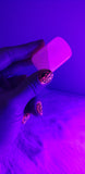 One Neon Pink Mangano Calcite tumbled stone under a black light